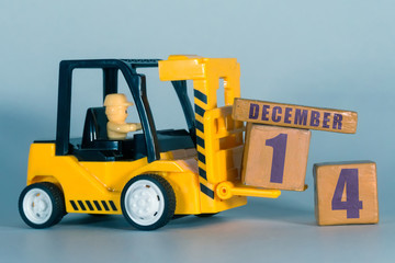 december 14th. Day 14 of month, Construction or warehouse calendar. Yellow toy forklift load wood cubes with date. Work planning and time management. winter month, day of the year concept