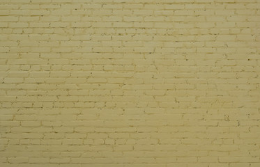Unique texture of an old brick wall painted with yellow whitewashed