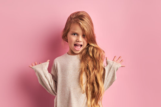 Portrait Of Surprised Caucasian Girl With Sweet Appearance Look At Camera, Have Long Hair With Long Waves, Wearing White Blouse, Isolated Pink Background