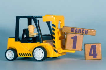 march 14th. Day 14 of month, Construction or warehouse calendar. Yellow toy forklift load wood cubes with date. Work planning and time management. spring month, day of the year concept