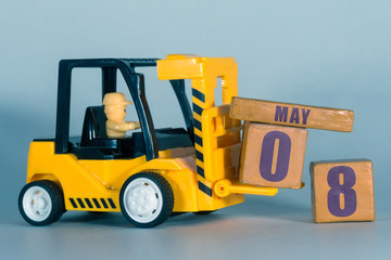 may 8th. Day 8 of month, Construction or warehouse calendar. Yellow toy forklift load wood cubes...