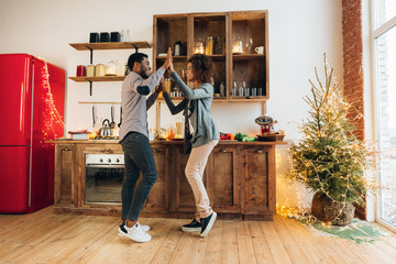 Young african-american couple dancing in kitchen, copy space