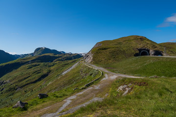 Fototapeta premium Through the Vikafjell a pass road to Vik is located in the kommunes Hordaland and Sogne og Fjordane. Mountains with summer snow on background. July 2019