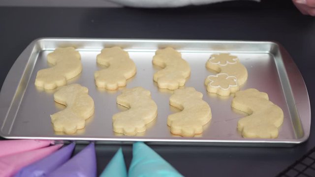 Decorating unicorn sugar cookies with multi-color royal icing.