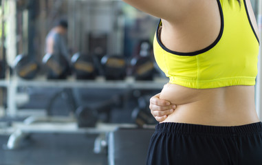 Fototapeta premium Close up woman holding excessive fat lower back. Woman overweight abdomen. Woman diet lifestyle concept reduce belly and shape up healthy stomach muscle. Weight loss, slim body, healthy concept.
