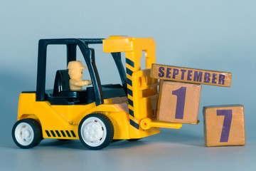 september 17th. Day 17 of month, Construction or warehouse calendar. Yellow toy forklift load wood cubes with date. Work planning and time management. autumn month, day of the year concept