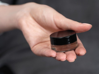 Woman's beauty blogger hands holding bottles and tubes spa professional hi-end cosmetics applies sample tone color on skin with copyspace