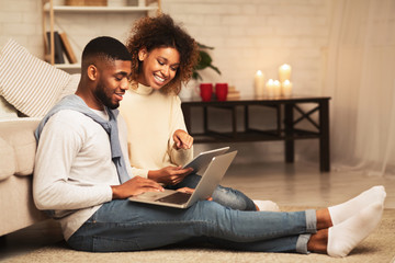 Happy african-american spouses browsing internet on gadgets