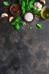 Culinary background with traditional italian spices : basil, garlic, sea salt, pepper and olive oil. Top view with copy space.