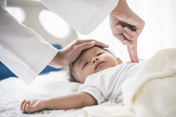 The doctor is using two fingers to press down in the middle of the baby's chest, which is CPR in the case that the child stops breating, to health care and insurance concept.