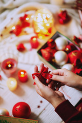 Celebrating New Year and Christmas at home, a girl wraps and holds gifts in a cozy atmosphere