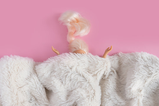 The dolls head and hands are visible from under the synthetic white fur. Minimalism concept, 80s style. Happy holidays greeting card