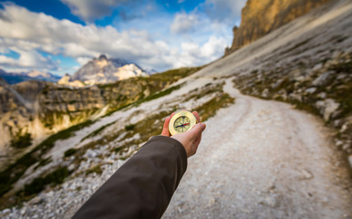 Fototapeta na wymiar Explorer searching direction with compass in summer mountains, point of view.