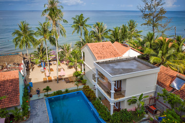 Fototapeta na wymiar Phu Quoc island, Vietnam - March 30, 2019: hotel with a pool on the coastline of the Indian Ocean, high palm trees, sea horizon