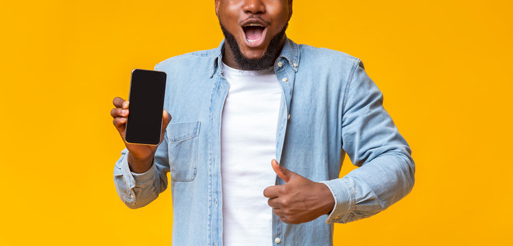 African guy demonstrating blank smartphone and gesturing thumb up