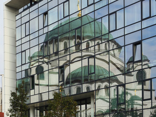 Modern and traditional architecture, lifestyle. Reflection of Saint Sava Church in windows of modern building. Travel Serbia, Balkan explorer background