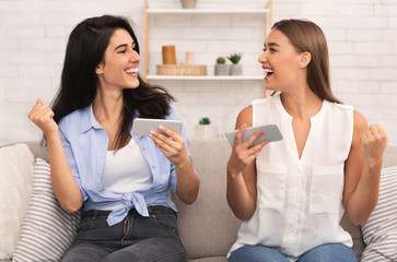 Two Girls Playing Games On Phones Gesturing Yes Sitting Indoor