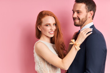 Caucasian couple of young two person stand hugging, posing at camera. Woman has red hair, man has beard