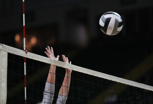 A middle blocker tries to stop a ball at the net