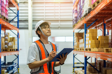 Warehouse worker checking inventory compare with stock list in hand.