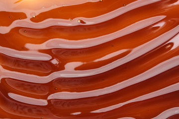 The texture of the wavy caramel closeup. View from above. Spreading caramel.