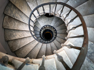 Ancient spiral staircase with decorated wrought iron handrails and marble steps inside an old...