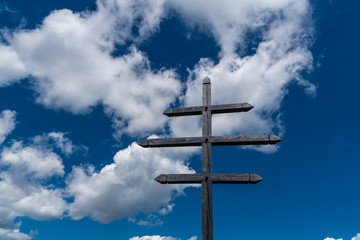Wetterkreuz mit drei Balken gegen blauem Himmel mit weißen Wolken