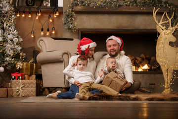 Image of parents with son at fireplace, deer with garland in room