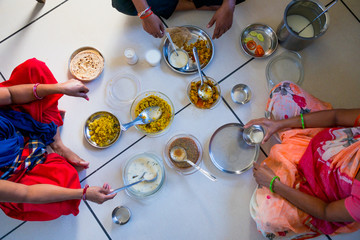hands of indian men and women having traditional gujarati thali  lunch on floor for being of low caste