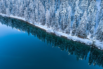 Forest covered with snow and alpine lake. 