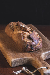 wholemeal bread sliced on a wooden board with a black background