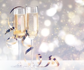 Glasses of champagne with curly ribbon on dark background