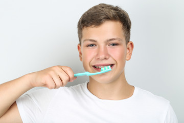 Young man with toothbrush on grey background