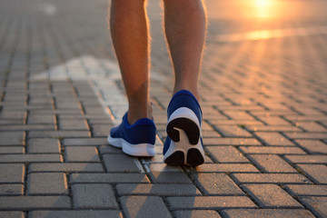 Feet on the road arrow in the rays of the setting sun