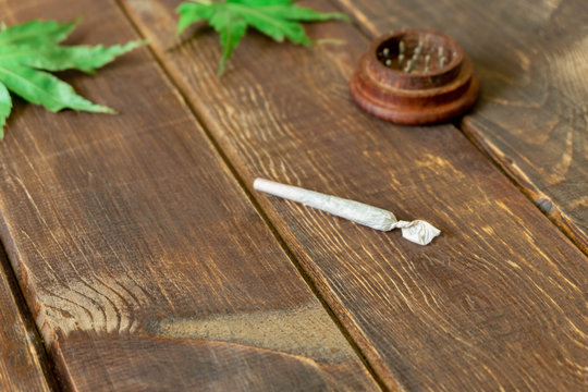 Rolled cannabis (marijuana) cigarette on wooden table