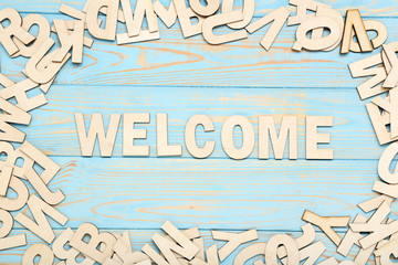 Word Welcome by wooden letters on blue table