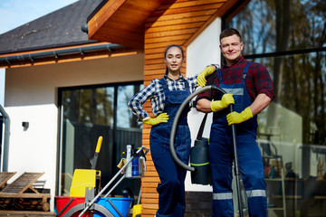 Two caucasian cleaners do perfect job, stand after cleaning house. People, housekeeping, cleaning...
