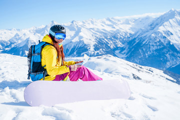 Fototapeta na wymiar Image of snowboarder woman in helmet with map in her hands sitting on mountain slope