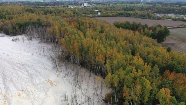 Aerial view of open pit kaolin clay mine (kaolinite quarry) surrounded by autumn landscape with colorful trees - landscape panorama of Poland from above, Europe