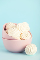 Marshmallows in bowl on blue background. Minimalism concept