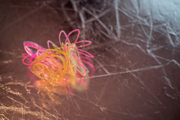 Broken, tangled plastic spring toy lies on dark background with bokeh