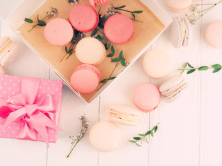 Gift box and macarons on whie table background with copy space to write. several white and pink sweet tender macaroons on a white background