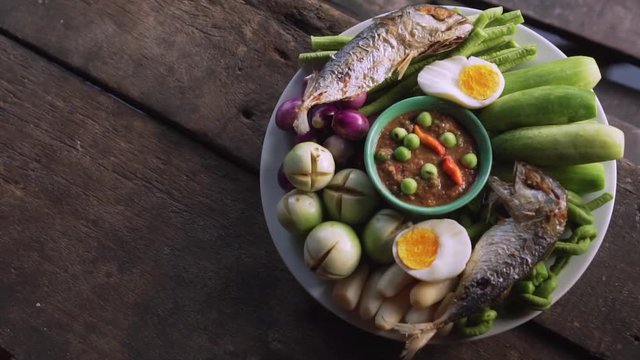 Set plate of fried mackerel with shrimp paste sauce and vegetables. Thai dish. slow motion. Top view shot.