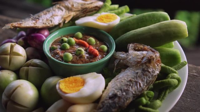 Set plate of fried mackerel with shrimp paste sauce and vegetables. Thai dish. slow motion. Tilt up shot