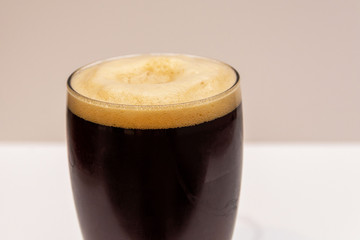 Dark beer with foam in a transparent glass