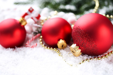 Christmas baubles with fir tree branches on white snow