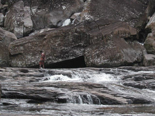 Local man walking between the rocks at Ramboda Waterfall in Sri Lanka