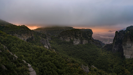 Naklejka premium Glowing Meteora sunrise with Holy Trinity Monastery under ceiling of fog