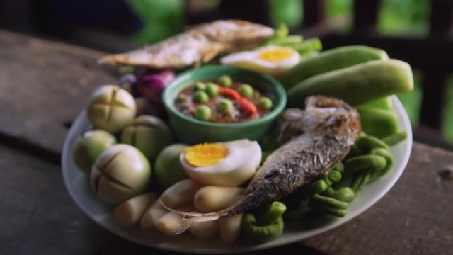 Set plate of fried mackerel with shrimp paste sauce and vegetables. Thai dish. slow motion. from out to in focus.