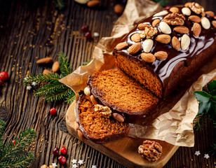 Gingerbread cake, Christmas gingerbread cake covered with chocolate and decorated with nuts and almonds on the holiday table, copy space, top view. Christmas, traditional dessert - obrazy, fototapety, plakaty